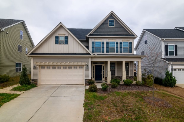 A 2-floor suburban house with a garage and a lawn
