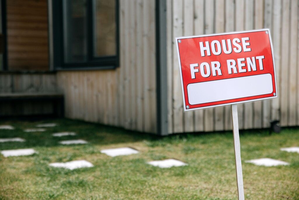 Sign that says House For Rent in front of a building