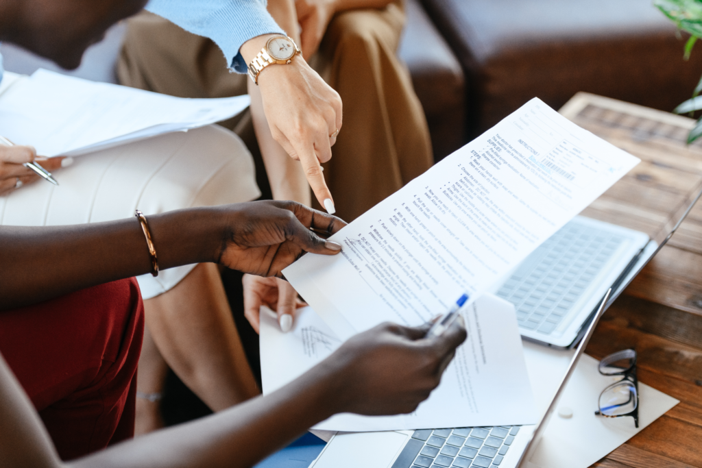 : A woman holding out an important document while another points