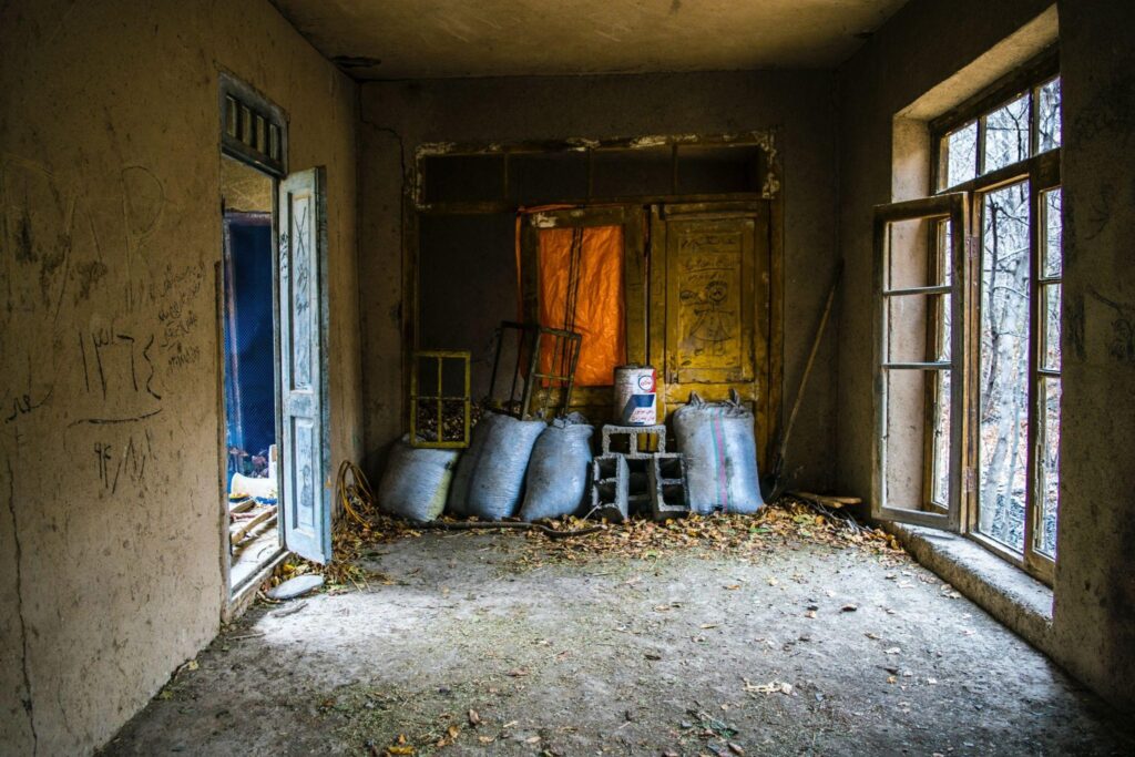 The interior of an old home with aged wooden frames and dry leaves